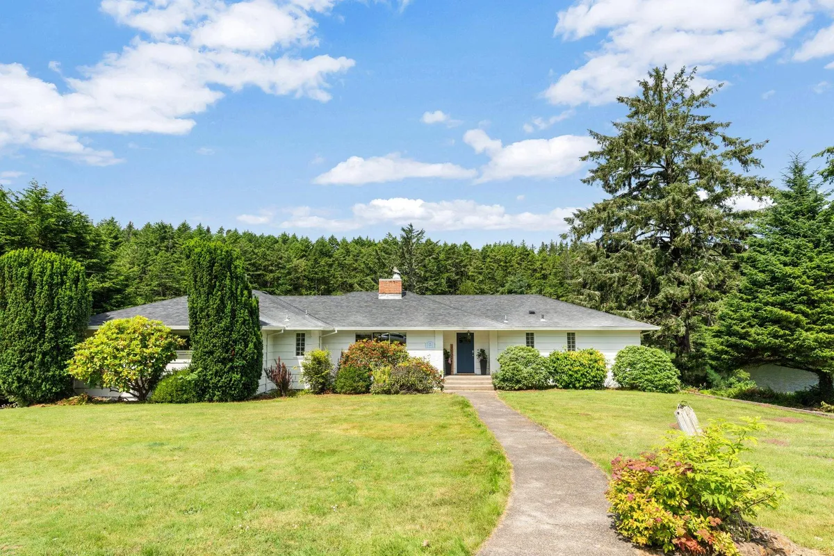 A well-manicured garden and pathway lead up to the front entrance of the home, surrounded by lush landscaping. The scene feels peaceful and welcoming, hinting at the privacy and exclusivity of the retreat.